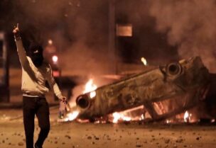 بيروت - صورة تُظهرأحد شبيحة حزب الله وحركة أمل أمام سيارة قاموا بإحراقها وسط مدينة بيروت