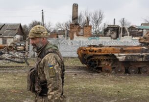 جندي أوكراني يسير الى جانب آليات مدمَّرة (رويترز)
