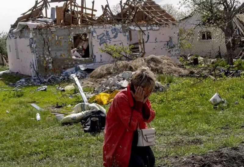 امرأة في حالة من القلق والضيق خارج بيتها المدمر في قرية فيلخيفكا في خاركيف (رويترز)