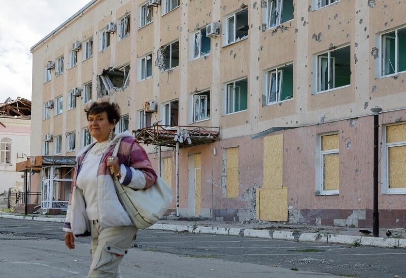 امرأة أمام مبنى مشظّى في لوغانسك أوكرانيا (رويترز)