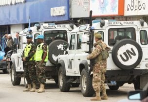 عنصر من الجيش اللبناني وجنود حفظ سلام تابعين للأمم المتحدة (اليونيفيل) يقفون إلى جانب مركبات لليونيفيل في مدينة العاقبية