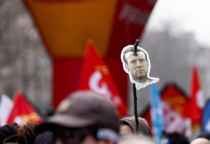 متظاهر يحمل صورة للرئيس الفرنسي إيمانويل ماكرون على عصا خلال مسيرة ضد خطة الحكومة لإصلاح نظام المعاشات التقاعدية في باريس