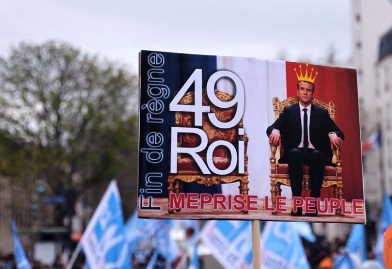 متظاهرون يحملون لافتة تصور الرئيس الفرنسي إيمانويل ماكرون كملك خلال مظاهرة