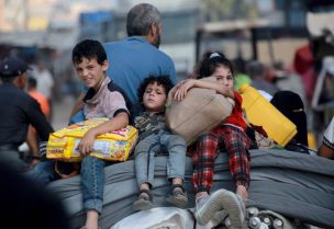 أطفال فلسطينيون يركبون على ظهر عربة وهم يحملون أمتعتهم في غزة