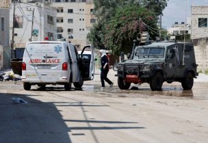 آلية إسرائيلية تقف مقابل سيارة إسعاف فلسطينية خلال العمليات العسكرية في جنين