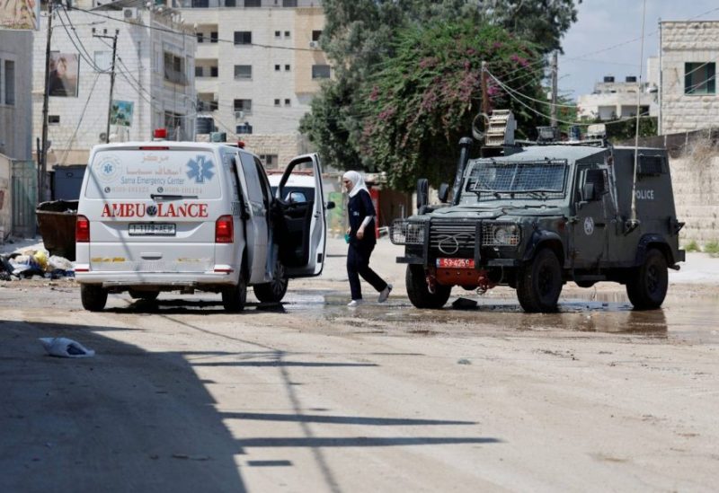 آلية إسرائيلية تقف مقابل سيارة إسعاف فلسطينية خلال العمليات العسكرية في جنين