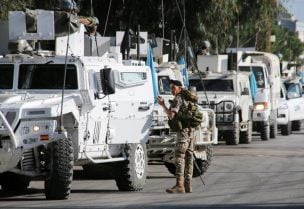 جندي من الجيش اللبناني يقف بالقرب من مركبات قوات حفظ السلام التابعة للأمم المتحدة (اليونيفيل) في مرجعيون