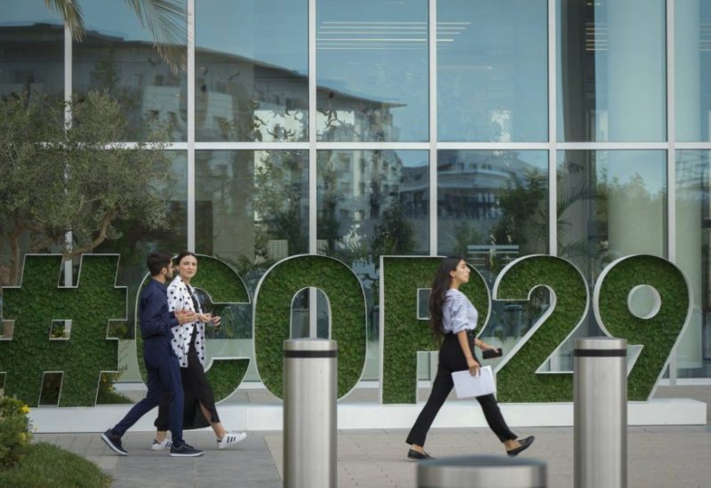 أشخاص يمرون أمام مقرعقد مؤتمر «كوب 29» في باكو