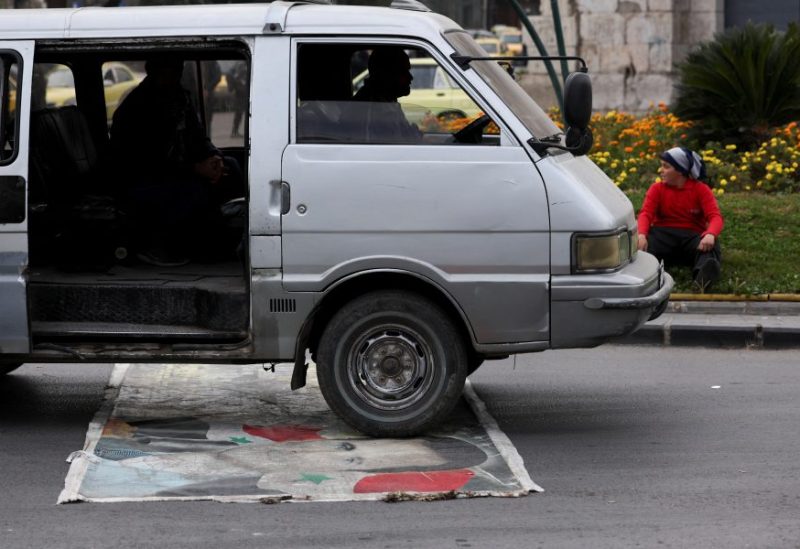 سيارة تسير فوق صورة بشار الأسد وسط العاصمة دمشق - رويترز