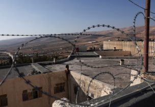 أفراد فرق الإنقاذ يقفون على سطح سجن صيدنايا في سوريا. رويترز