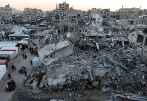 فلسطينيون يسيرون بين أنقاض المباني في خان يونس. رويترز