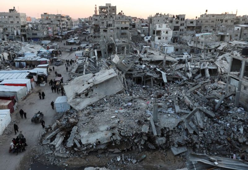 فلسطينيون يسيرون بين أنقاض المباني في خان يونس. رويترز