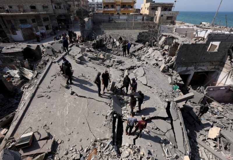 فلسطينيون يتفقدون موقع غارة إسرائيلية على مبنى سكني في دير البلح. رويترز