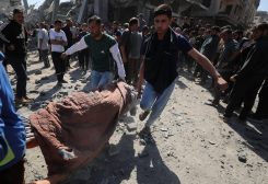 فلسطينيون يحملون جثة شهيد أثناء بحثهم عن شهداء في موقع غارة إسرائيلية على منزل في جباليا شمال قطاع غزة في 2 مايو/أيار 2025. رويترز