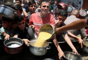 فلسطينيون ينتظرون استلام الطعام المطبوخ في مطبخ خيري في جباليا شمال قطاع غزة، 19 مايو/أيار 2025. رويترز