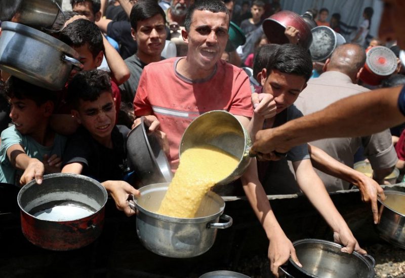 فلسطينيون ينتظرون استلام الطعام المطبوخ في مطبخ خيري في جباليا شمال قطاع غزة، 19 مايو/أيار 2025. رويترز