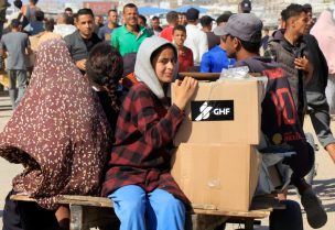 أشخاص يركبون عربة بينما يتجمع فلسطينيون يسعون للحصول على مساعدات بالقرب من موقع لتوزيع المساعدات تديره مؤسسة غزة الإنسانية المدعومة من الولايات المتحدة في رفح جنوب قطاع غزة، 27 مايو/أيار 2025. رويترز