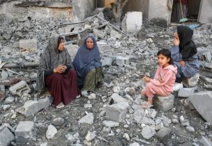 فلسطينيون يجلسون على الأنقاض في موقع غارة إسرائيلية على منزل في جباليا، شمال قطاع غزة، 30 مايو/أيار 2025. رويترز