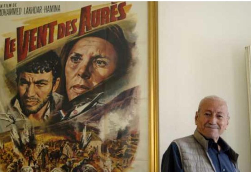 المخرج الراحل مع ملصق فيلم "ريح الأوراس"