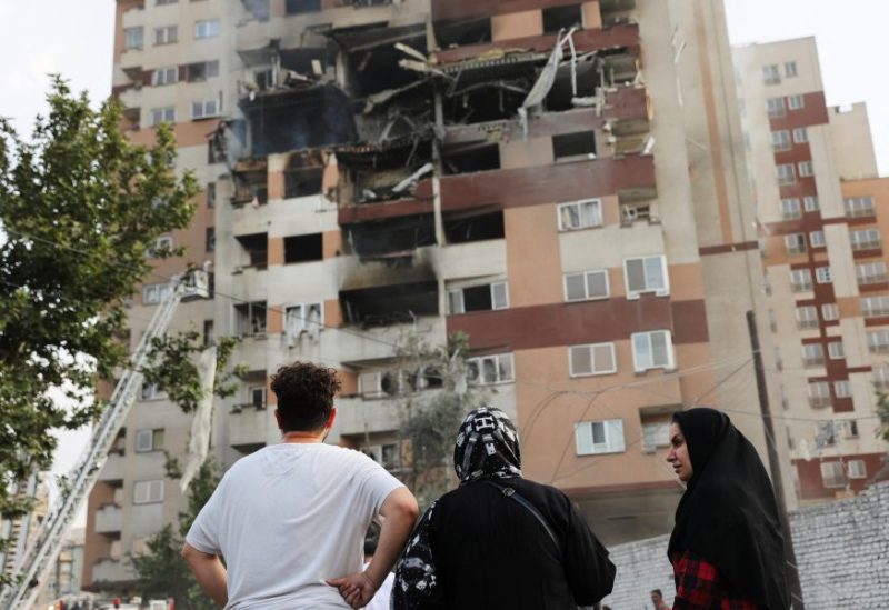 أشخاص ينظرون إلى مبنى متضرر في أعقاب الغارات الإسرائيلية، في طهران، إيران، 13 يونيو/حزيران 2025. رويترز