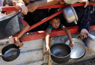 طفل يحمل إناءً بينما يتجمع الفلسطينيون لتلقي الطعام من مطبخ خيري وسط أزمة الجوع في مدينة غزة، 22 يوليو/تموز 2025. رويترز