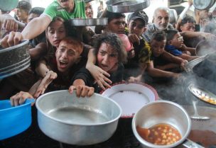 فلسطينيون يتجمعون لتلقي الطعام المطبوخ من قبل مطبخ خيري، في شمال قطاع غزة. رويترز