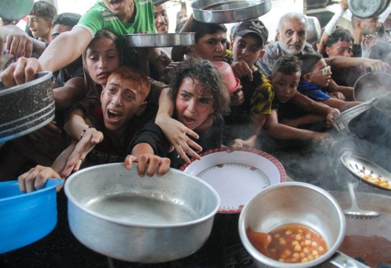 فلسطينيون يتجمعون لتلقي الطعام المطبوخ من قبل مطبخ خيري، في شمال قطاع غزة. رويترز