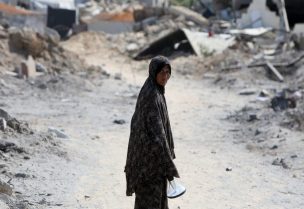 امرأة فلسطينية تنظر إلى موقع منازل دمرت خلال غارة إسرائيلية، في الجزء الغربي من النصيرات، وسط قطاع غزة، 29 يوليو 2025. رويترز