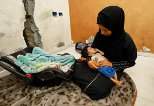 أميرة مطير تحمل رضيعها عمار في مدينة غزة في صورة بتاريخ 5 أغسطس/آب الجاري (رويترز)