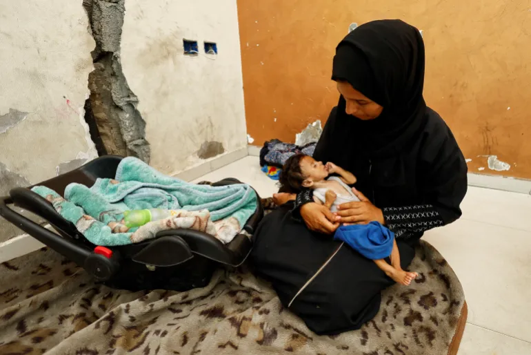 أميرة مطير تحمل رضيعها عمار في مدينة غزة في صورة بتاريخ 5 أغسطس/آب الجاري (رويترز)