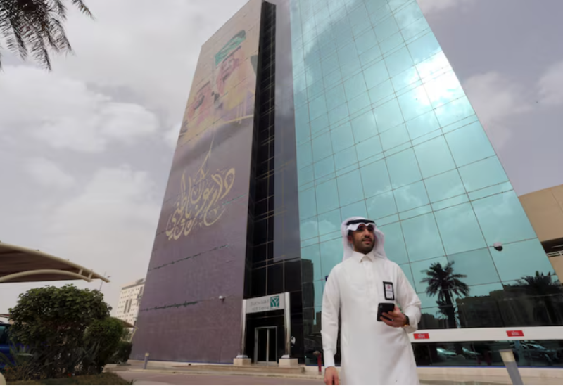أحد المارة يسير أمام مقر البنك الأهلي السعودي بالرياض-رويترز