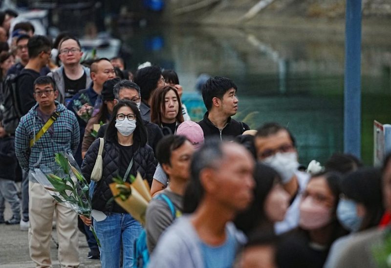 الناس يصطفون لوضع الزهور في نصب تذكاري مؤقت بالقرب من مجمع وانغ فوك كورت السكني لتكريم ضحايا الحريق المميت الذي اندلع في مجمع وانغ فوك كورت السكني، في تاي بو، هونغ كونغ، الصين، 30 نوفمبر 2025. رويترز