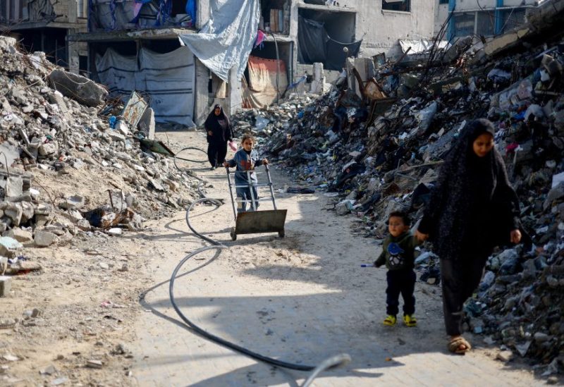 فلسطينيون يمرون بجانب أنقاض مبان سكنية دُمرت خلال العدوان الإسرائيلي، في جباليا، شمال قطاع غزة. رويترز