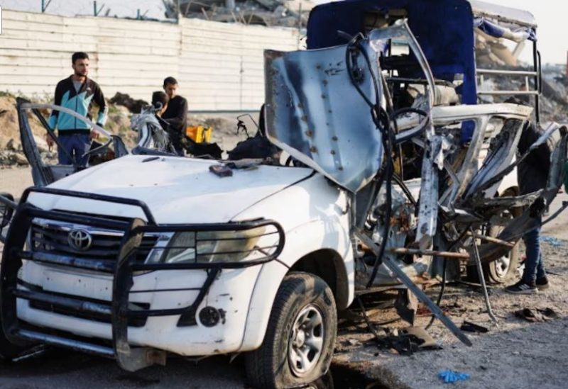 فلسطينيون يتفقدون موقع غارة جوية إسرائيلية استهدفت سيارة شرطة في وسط قطاع غزة