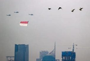 طائرات هليكوبتر تابعة للقوات الجوية الإندونيسية تحمل علم إندونيسيا تحلق فوق مبان شاهقة خلال احتفالات عيد استقلال البلاد الـ 76 في جاكرتا بصورة من أرشيف رويترز.