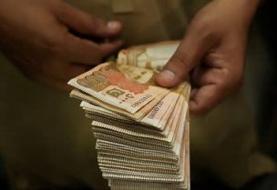 تاجر يعدّ أوراقا نقدية من الروبية الباكستانية في بيشاور بباكستان يوم 29 يوليو تموز 2025. تصوير: فياض عزيز - رويترز