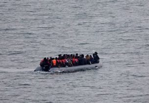 مجموعة مهاجرين يستقلون زورقا مطاطيا لعبور القنال الإنجليزي من شمال فرنسا في صورة من أرشيف رويترز.