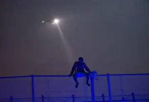 مهاجر أفريقي يجلس فوق سياج حدودي مغطى بأسلاك شائكة بين المغرب وجيب مليلية الإسباني في شمال أفريقيا خلال محاولة أخيرة للعبور إلى الأراضي الإسبانية في صورة من أرشيف رويترز.
