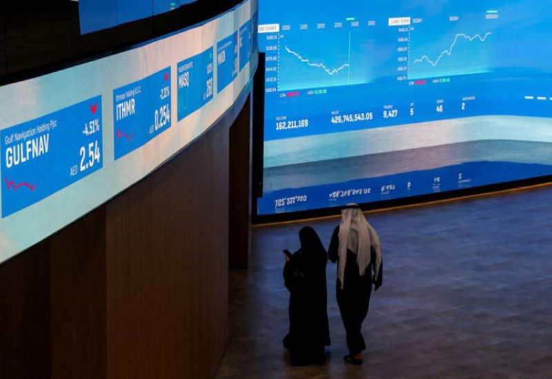 شخصان يسيران أمام شاشات تعرض بيانات الأسهم في سوق دبي المالي يوم 30 ديسمبر كانون الأول 2025. تصوير: عمرو الفقي - رويترز