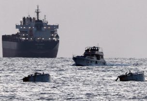 جنود إسرائيليون على متن سفينة تحمل شعار أسطول الصمود العالمي وخلفها سفينة شحن كما يبدو من أسدود في جنوب إسرائيل يوم 19 مايو أيار 2026. تصوير: أمير كوهين - رويترز
