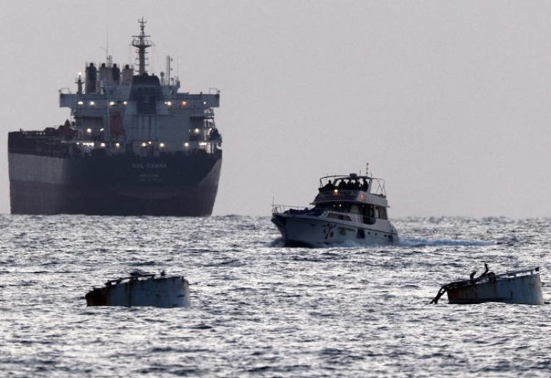 جنود إسرائيليون على متن سفينة تحمل شعار أسطول الصمود العالمي وخلفها سفينة شحن كما يبدو من أسدود في جنوب إسرائيل يوم 19 مايو أيار 2026. تصوير: أمير كوهين - رويترز