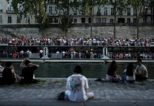 قارب يمر بجانب أشخاص يجلسون على ضفاف نهر السين، حيث وصلت درجات الحرارة إلى 35 درجة خلال فترة من الطقس الحار في باريس يوم 25 مايو أيار 2026. تصوير: توم نيلسون - رويترز