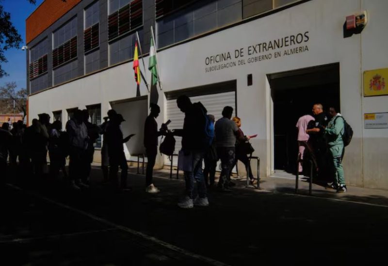 أشخاص يصطفون لتقديم وثائقهم في مكتب حكومي لشؤون الهجرة بهدف تسوية أوضاعهم القانونية في مدينة ألميريا الإسبانية