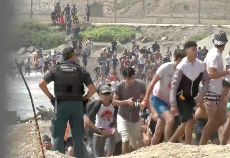 مهاجرون يسيرون بجانب أحد أفراد الحرس المدني التابع لـ USECIC بعد أن عبروا سباحةً حدود سبتة الإسبانية قادمين من الجانب المغربي للوصول إلى السياج الحدودي، في سبتة، إسبانيا، 30 يوليو 2026، رويترز
