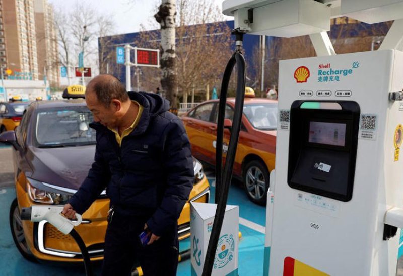 رجل يقوم بشحن سيارة أجرة في محطة تابعة لشركة «شل» مخصصة للسيارات الكهربائية في بكين بصورة من أرشيف رويترز.