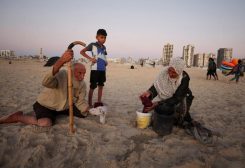 امرأة فلسطينية نازحة مع عائلتها تغسل ملابس في دلو على شاطئ في مدينة غزة يوم 14 يوليو تموز 2026. تصوير: داوود أبو الكاس - رويترز