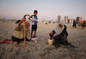 امرأة فلسطينية نازحة مع عائلتها تغسل ملابس في دلو على شاطئ في مدينة غزة يوم 14 يوليو تموز 2026. تصوير: داوود أبو الكاس - رويترز