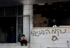 طفل فلسطيني يجلس بالقرب من مسجد متضرر في الضفة الغربية المحتلة
