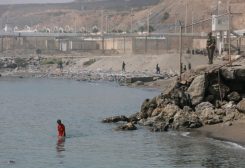 أحد أفراد قوات الأمن الإسبانية يقف حراسة بينما يمشي مهاجر قاصر من المغرب في المياه بعد عبوره إلى سبتة عن طريق البحر، في سبتة، إسبانيا، 1 أغسطس 2026. رويترز