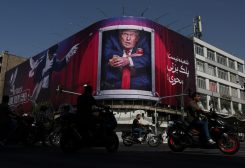 سيارات تمر بالقرب من لوحة إعلانية تصور الرئيس الأمريكي دونالد ترامب على أحد المباني في طهران. رويترز